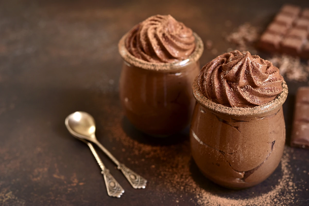 El Mousse de Chocolate Más Cremoso y Fácil. Dos vasitos de un cremoso mousse de chocolate casero, con una textura esponjosa y decorado con cacao en polvo, listos para servir.