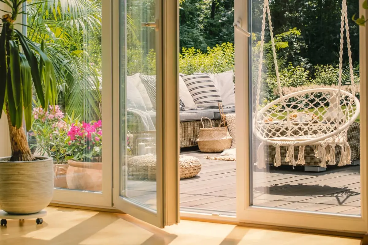 Terraza con puerta abierta, sillón colgante y paredes acabadas en durlock exterior