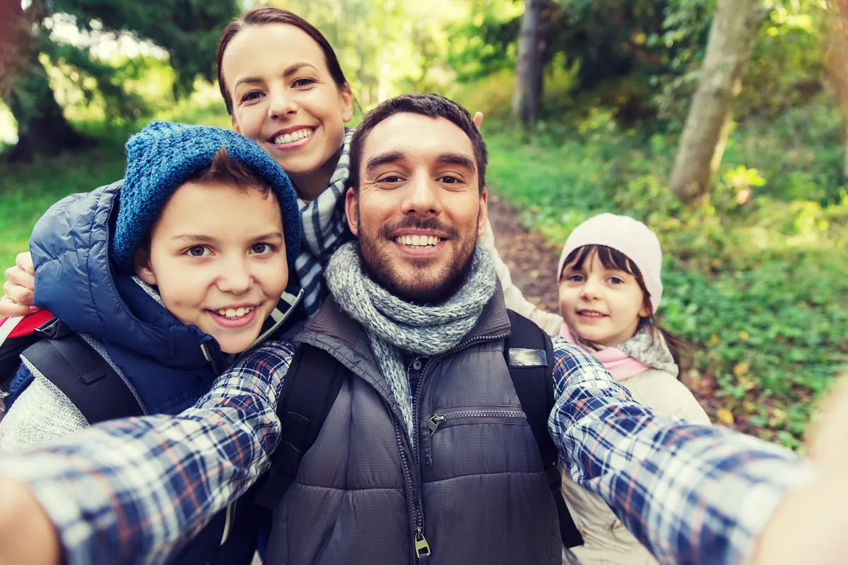 Familia feliz tomando una selfie durante una excursión, una idea de regalo de experiencia y aventura para el Día del Padre