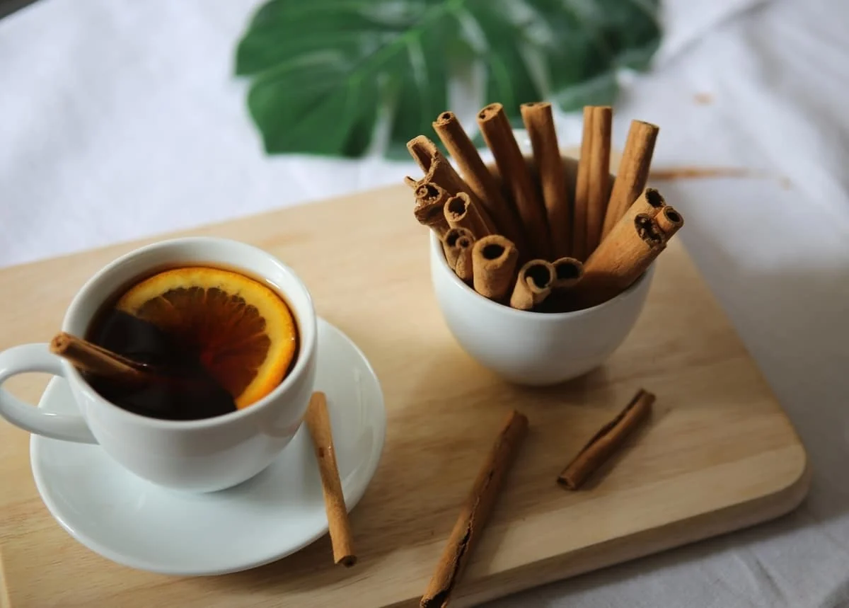 Taza de té con rodaja de naranja y canela en rama