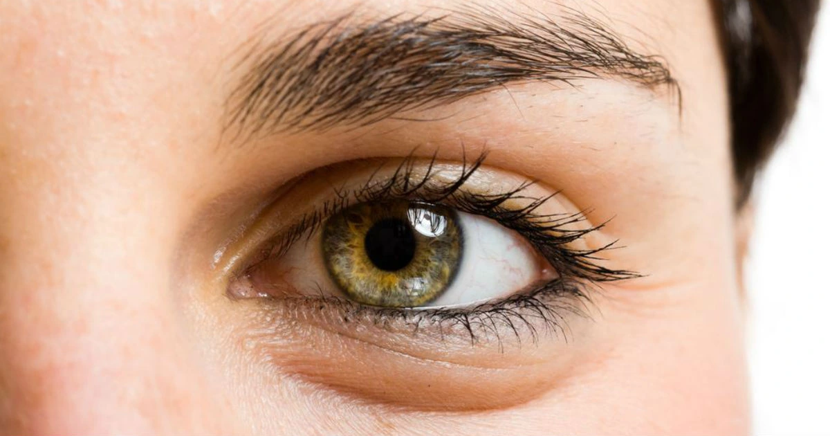 Close-up de ojo maquillado con sombra beige y pestañas curvadas