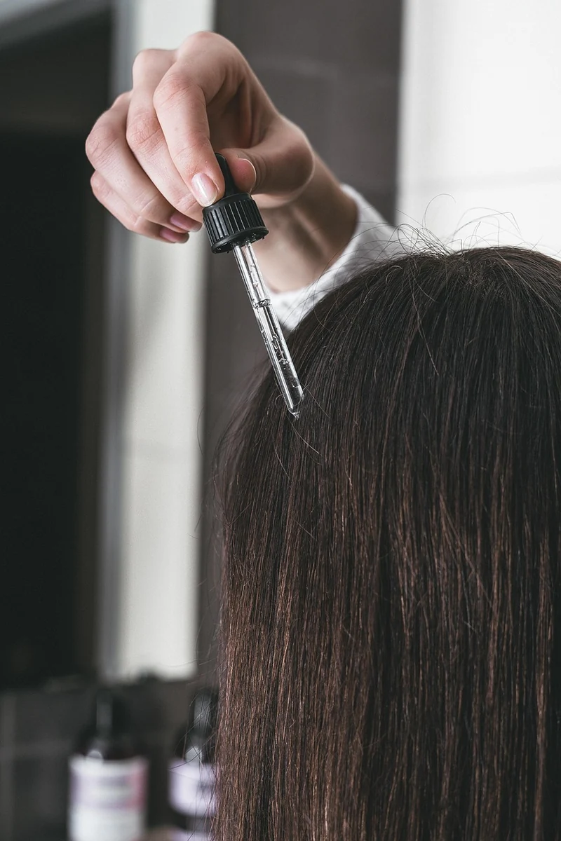 Aplicando un protector térmico en el cabello teñido, un paso esencial para protegerlo del daño por calor de planchas y secadoras y evitar que el color se deslave.