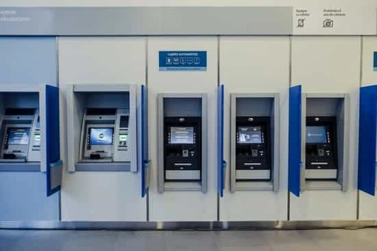Fila de cajeros automáticos azules y blancos empotrados en la pared de una sucursal bancaria