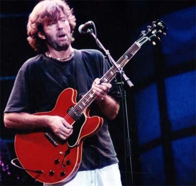guitarrista tocando guitarra eléctrica semihueca roja en escenario