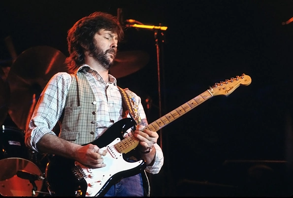 La imagen muestra a Eric Clapton tocando la guitarra