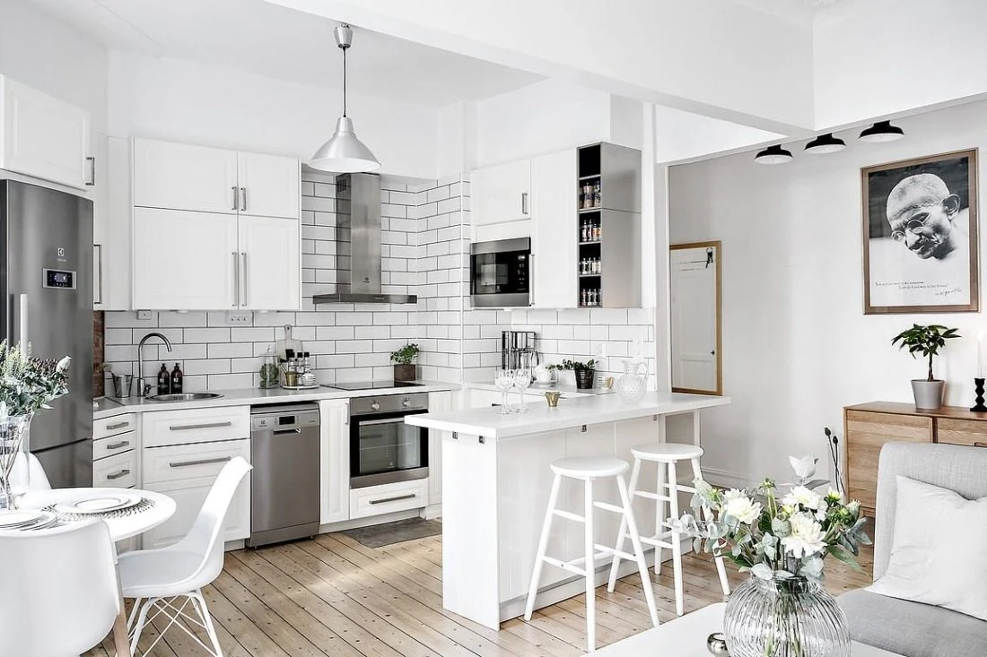 Cocina pequeña de estilo nórdico en blanco con barra desayunadora, muebles modernos y detalles minimalistas.