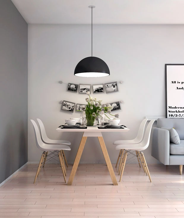 Pequeño comedor blanco con sillas Eames y mesa de madera clara con decoración de fotos colgantes