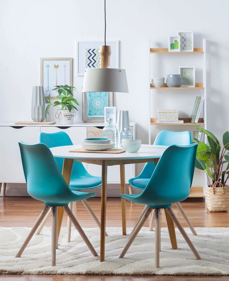 comedor pequeño con sillas turquesa y mesa redonda blanca de estilo escandinavo