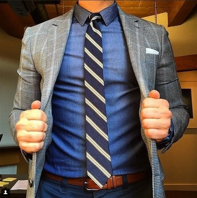 Ejemplo avanzado de cómo combinar estampados: un blazer de cuadros sobre una camisa de chambray y una corbata de rayas, variando la escala del patrón.
