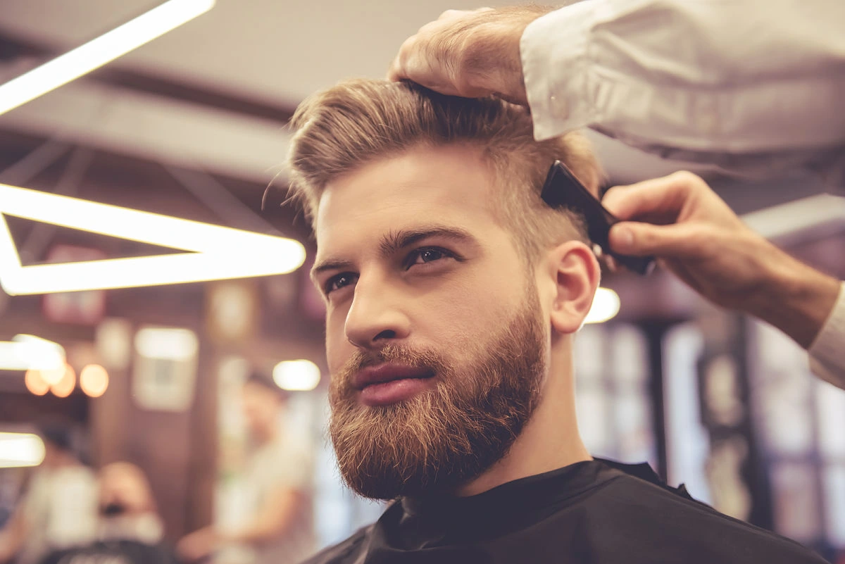 Corte de cabello moderno para hombre con fade alto y barba bien definida