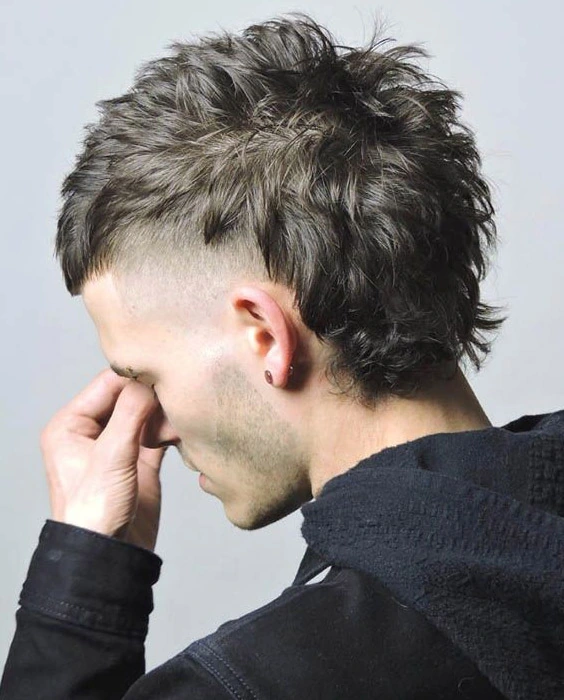 El Corte Mullet Masculino: Atrevido y en Tendencia Hombre luciendo un corte de pelo mullet moderno con lados cortos desvanecidos y cabello largo y texturizado en la parte superior y en la nuca, un estilo audaz y vanguardista.