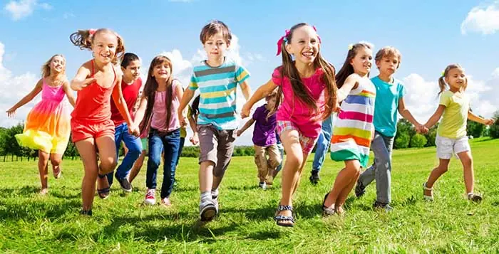cuándo es el día del niño en Argentina Grupo de niños y niñas felices corriendo de la mano en un campo, simbolizando la resiliencia, autoestima y seguridad emocional infantil.