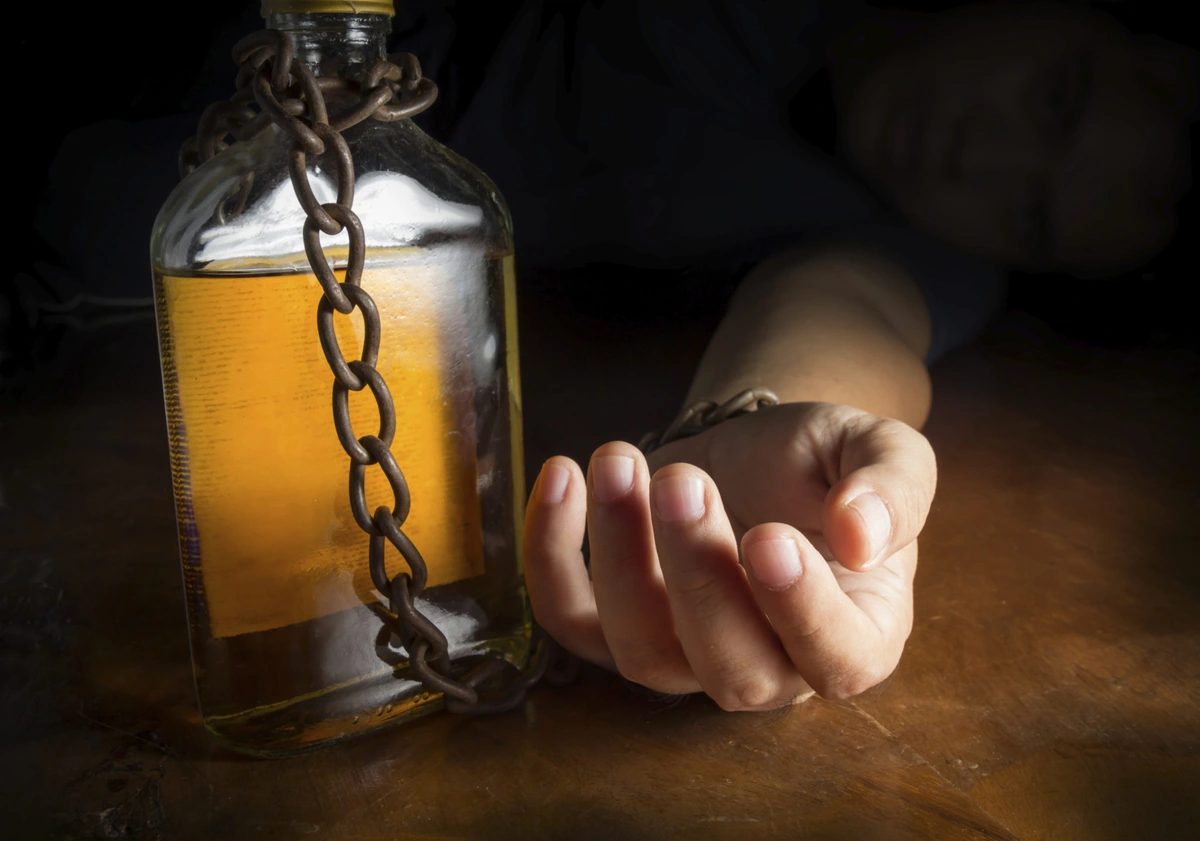 Hay estados con “ley seca” parcial. Mano de hombre encadenada a una botella de alcohol simbolizando adicción