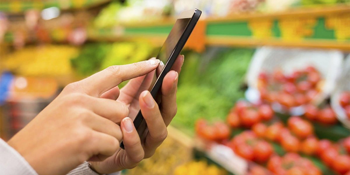 mujer con celular hacendo la compra de verduras