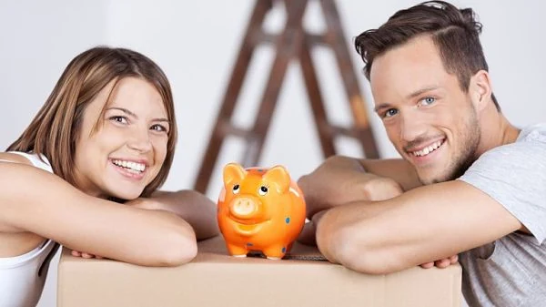 Pareja feliz con alcancía en forma de cerdito sobre una caja, simbolizando ahorro en pareja.