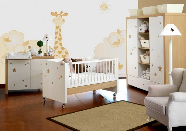 Habitación de bebé unisex con temática de jirafa, muebles blancos y de madera con estrellas, y vinilos de pared.