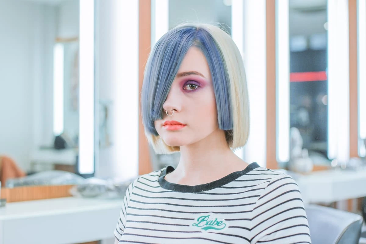 Mujer con un corte bob y un moderno diseño de coloración 'split dye', combinando un flequillo azul pastel con rubio platino, un ejemplo de la gama de colores de fantasía para cabello.
