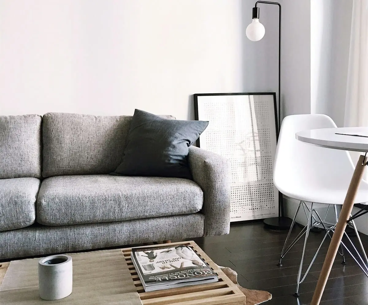 El Beneficio de un Espacio Ordenado Salón minimalista con sofá gris y suficiente espacio libre, un ejemplo de cómo evitar la acumulación de objetos en el diseño de interiores.