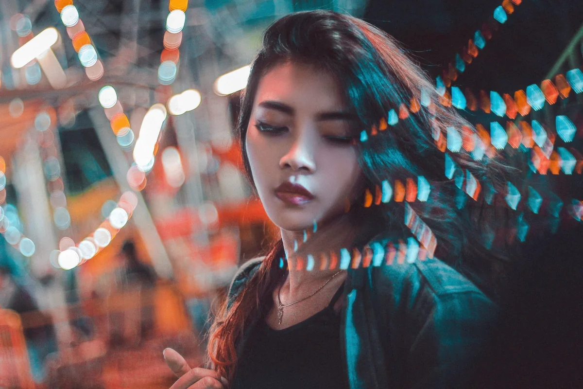 Mujer joven con luces de colores desenfocadas en una noche de feria