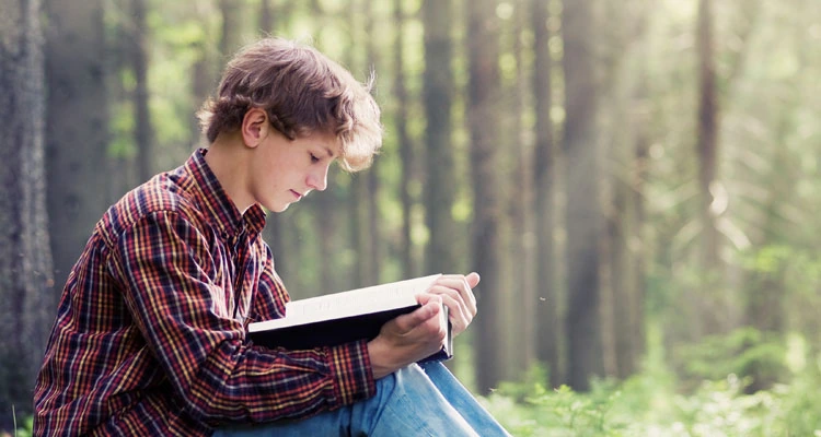 Joven leyendo un libro al aire libre