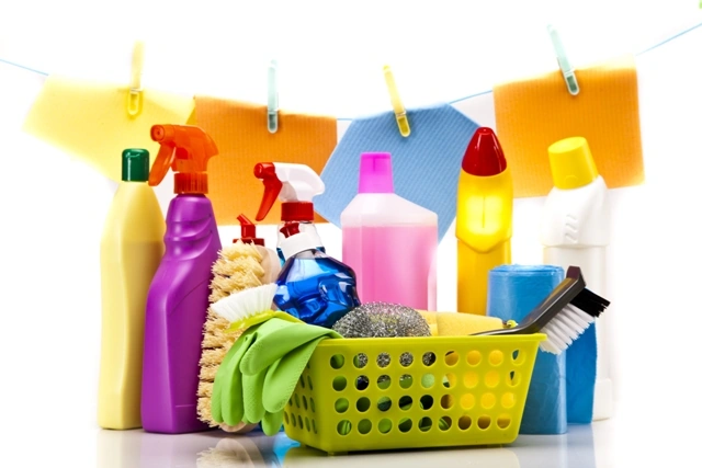 Canasta con productos de limpieza, cepillos y guantes, representando las herramientas caseras para remover manchas difíciles de la ropa.