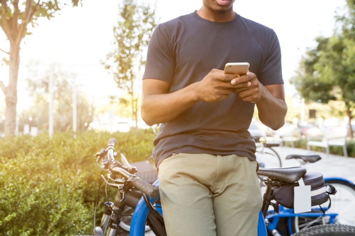 Hombre enviando mensajes con su mobil sentado en su bicicleta al aire libre