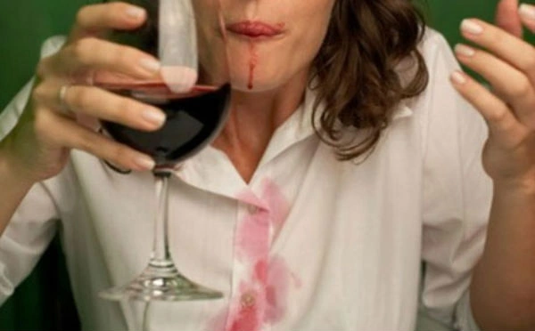 El vino tinto puede parecer una mancha imposible de eliminar, pero no es así si conoces algunos tips. mujer mancha su camisa blanca tomando vino tinto