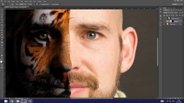 Adobe Photoshop: Edición Profesional y Fotomontajes Creativos. Captura de pantalla de la interfaz de Adobe Photoshop mostrando un fotomontaje que fusiona la mitad de la cara de un hombre con la de un tigre.