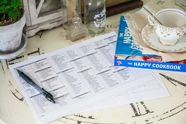 Organizador para Planificar tu Menú Plantilla de planificación del menú semanal y checklist de compras sobre una mesa, listos para organizar las comidas y ahorrar dinero.