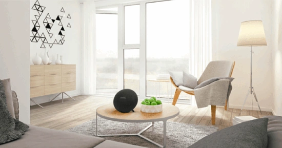 Parlante Harman Kardon colocado sobre una mesa en una sala moderna y luminosa.