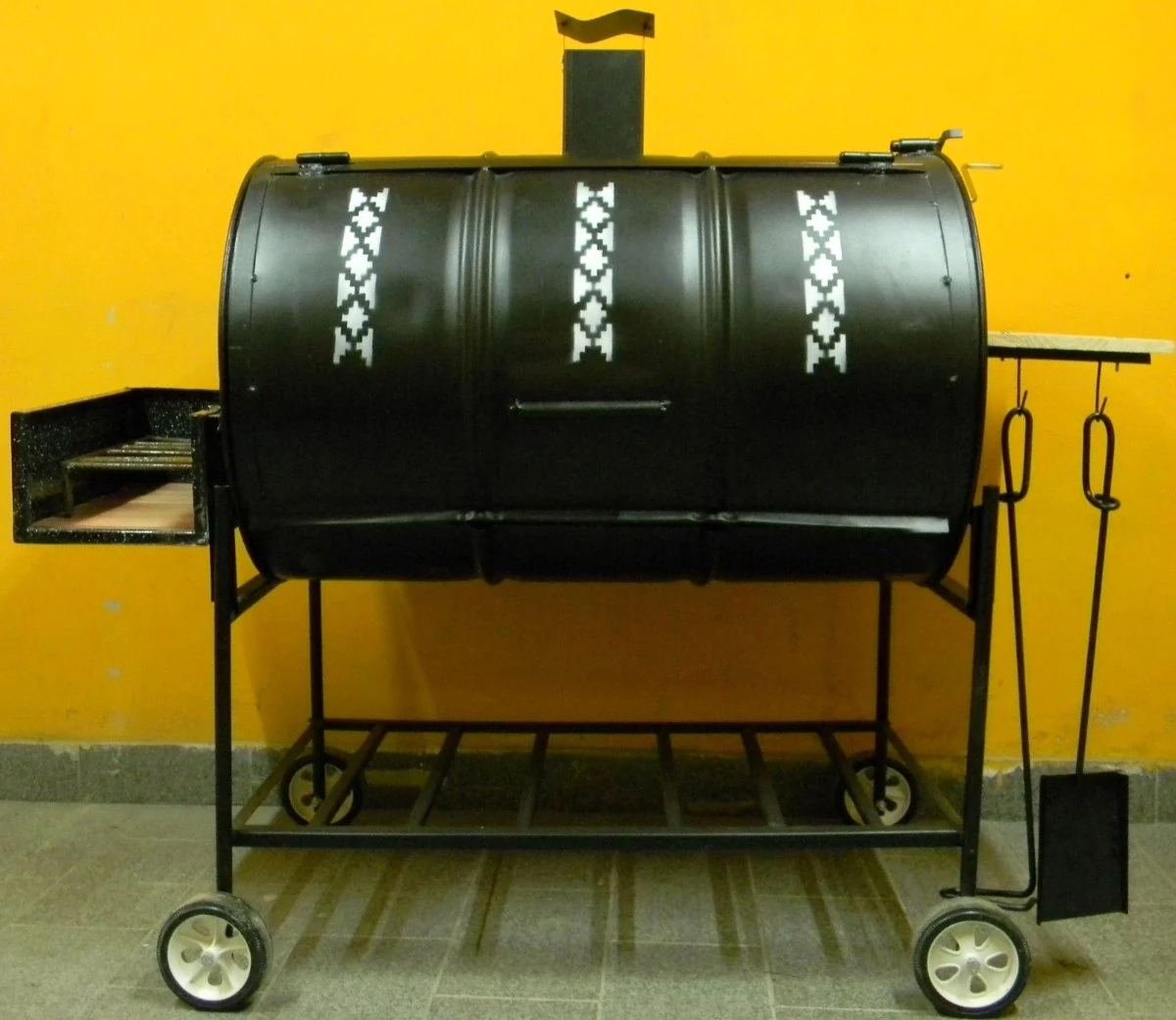 El secreto para una barbacoa tierna y llena de sabor ahumado. Ahumador offset tipo barril de color negro, diseñado para la cocción lenta y ahumado de barbacoa.