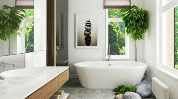 Baño moderno y luminoso decorado con plantas verdes, bañera exenta y paredes en tonos suaves tipo aguamarina o gris verdoso para un ambiente relajante.