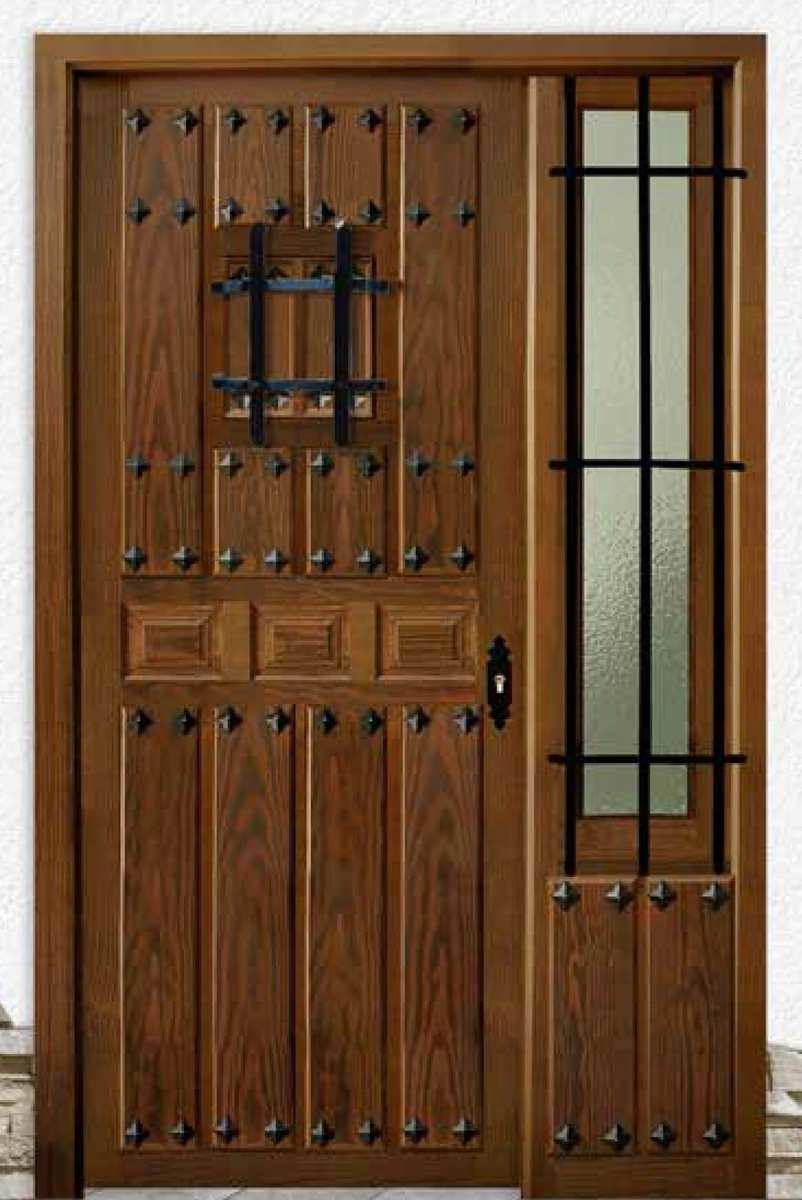 Puerta de entrada de madera maciza con tachuelas negras, mirilla enrejada y panel lateral con rejas