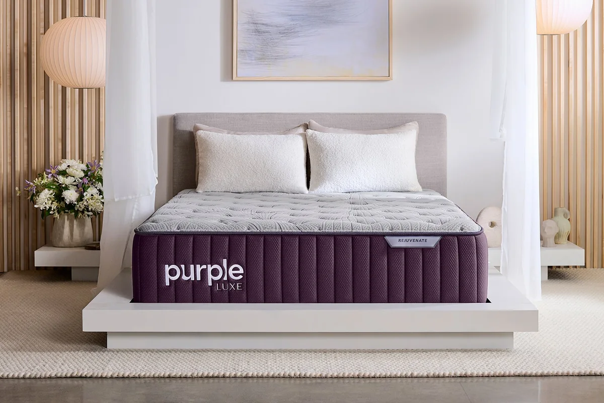 Colchón de muelles sobre base tapizada morada en dormitorio elegante: tecnología en colchones Purple