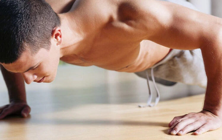 Rutinas de entrenamiento en casa con YouTube Hombre haciendo flexiones en casa, ejemplo de entrenamiento guiado por rutinas gratuitas de YouTube