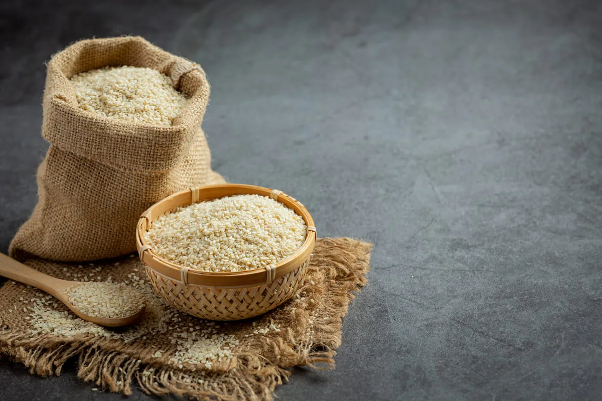 Guía para Cocinar Quinoa Perfecta Granos de quinoa cruda en un saco de yute y un cuenco, listos para aprender a cocinar la quinoa correctamente.