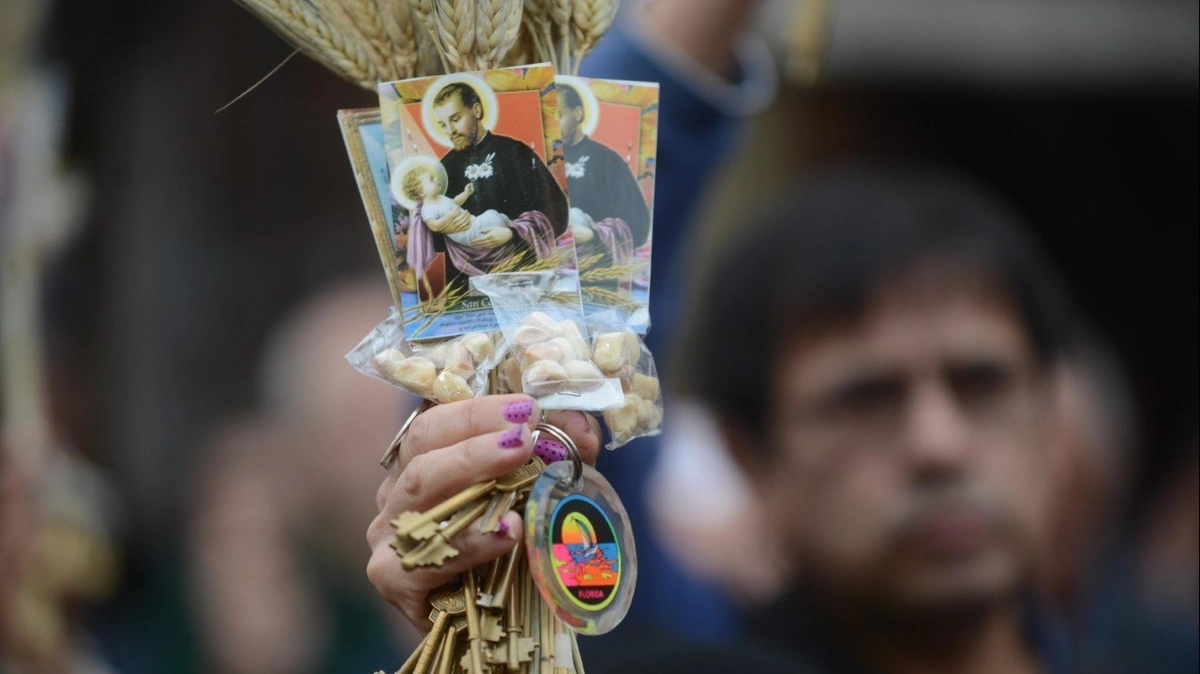 estampita de san cayetano en mano de una creyente, con espigas de trigo