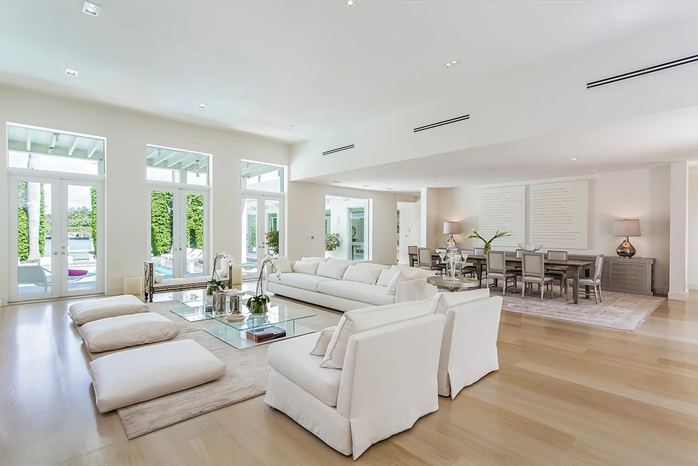 Sala de estar de la casa de Shakira con decoración minimalista en tonos blancos y detalles en plata y lila. Interior de la mansión de Shakira en Miami con diseño minimalista y toques de color.