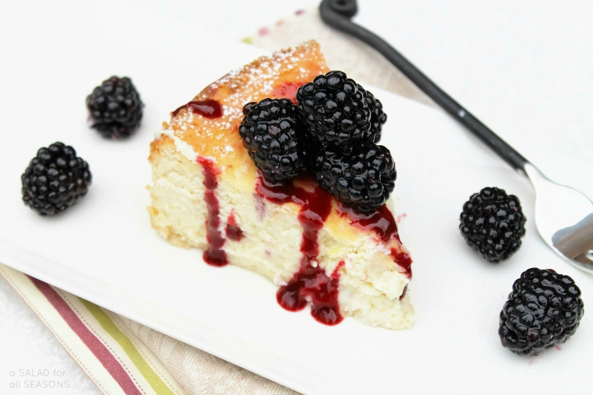 Porción de tarta de queso con moras frescas y coulis de frutos rojos