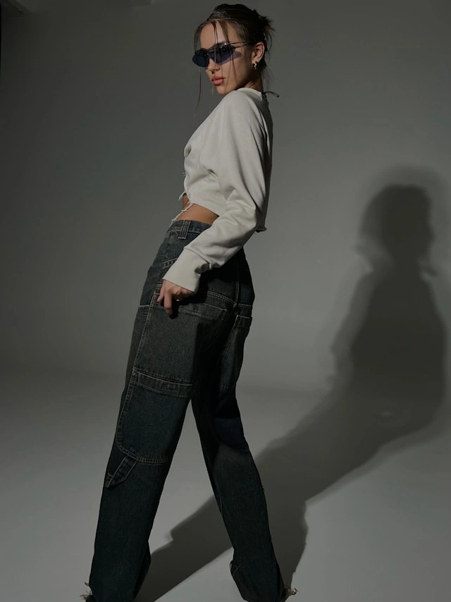 Mujer con actitud luciendo un look de tendencia oversize: pantalones cargo anchos y un crop top, un ejemplo del regreso del estilo de moda Y2K.
