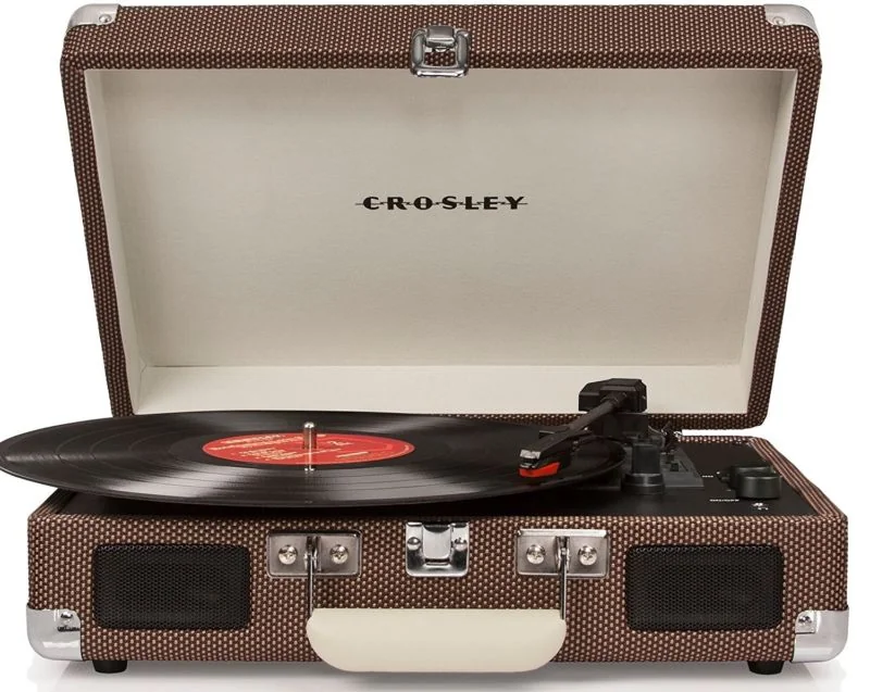 Tocadiscos portátil Crosley estilo maleta, color marrón y diseño vintage, abierto y con un disco de vinilo en el plato.