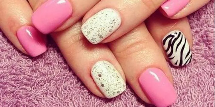 Ideas de Uñas con Animal Print y Glitter. Manicura divertida combinando uñas color rosa, esmalte blanco con glitter y una uña de acento con estampado de cebra (animal print).